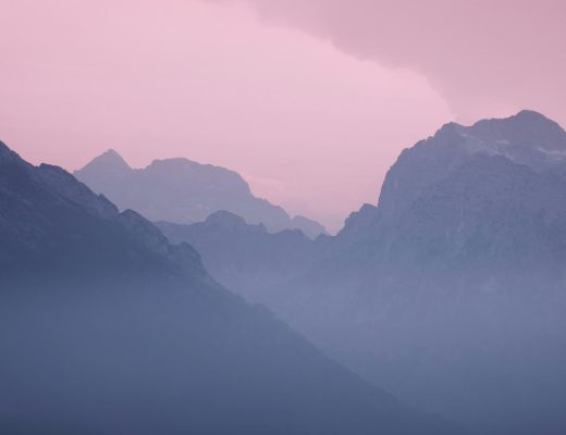 A mountain range with a pink sky in the background